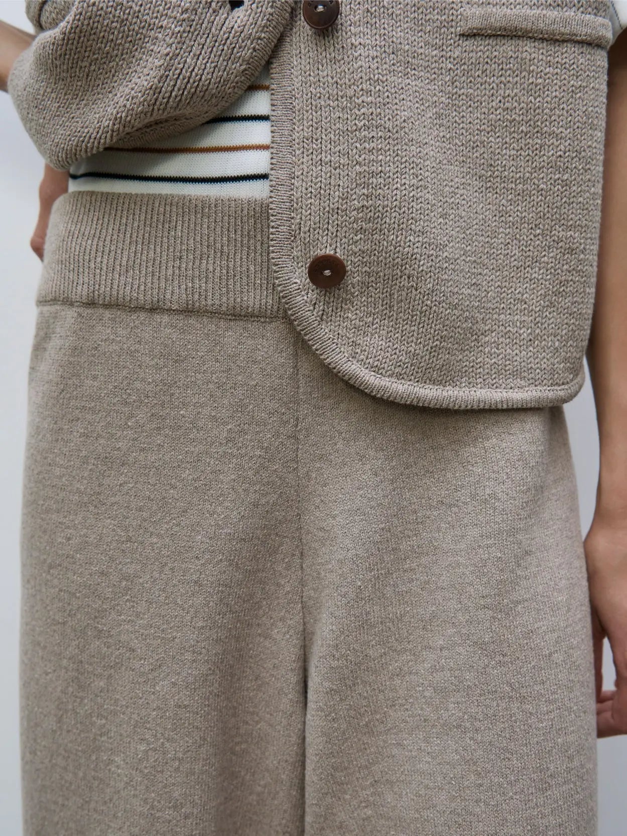 A pair of loose-fitting, knee-length, brownish-tan pants with an elastic waistband and ribbed cuffs at the hem is displayed on a plain white background. The material appears soft and slightly textured. Available as Cotton Knitted Pants Taupe by Cordera at Bassalstore in Barcelona.
