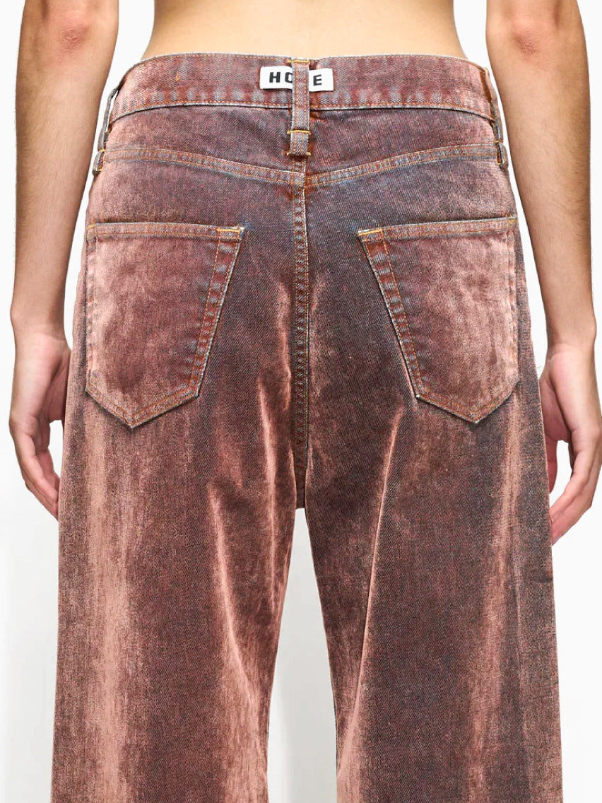 The HOPE Skid Jeans in Rust Flock are vintage-style, wide-legged brown jeans made from Organic Cotton with a faded finish and high waist. They feature classic five-pocket styling and prominent stitching, and are displayed laid flat against a white background.