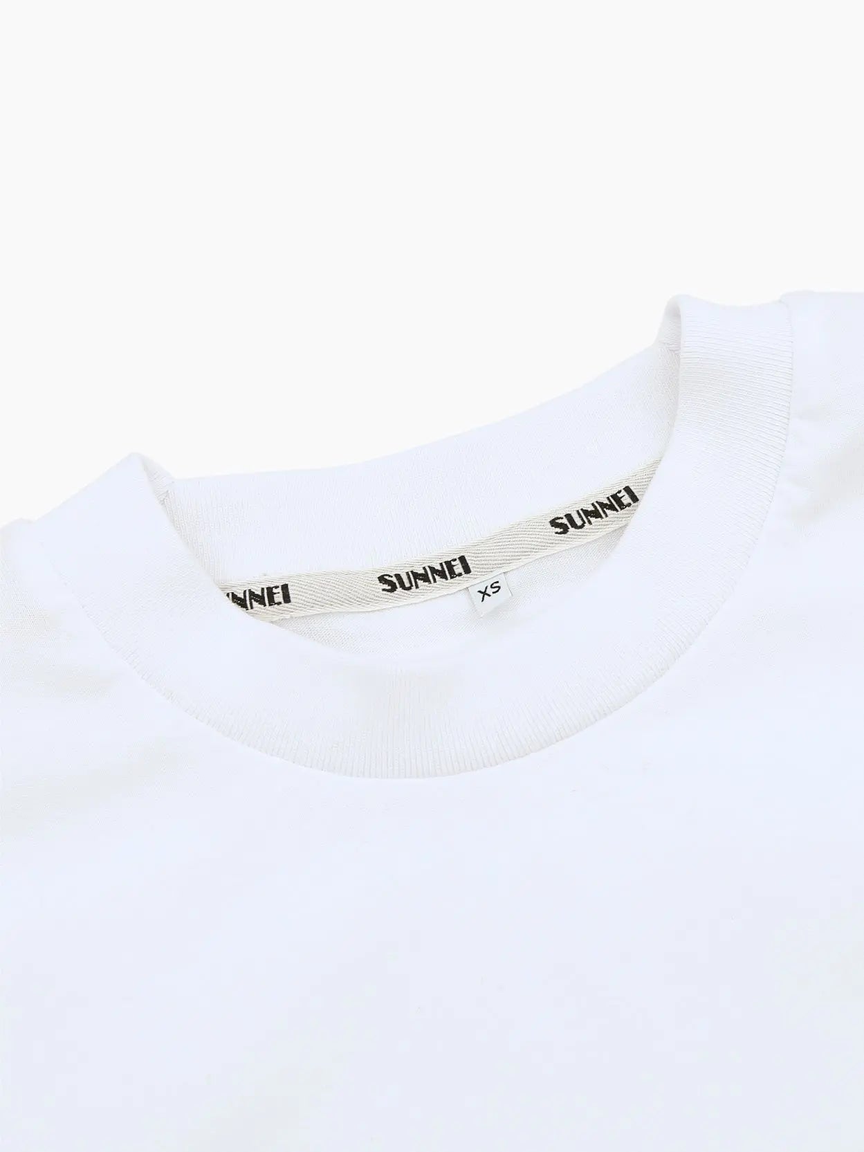 A white t-shirt with the text "JADOREREI SUNNEI" printed in black on the chest. The shirt has a classic crew neck and short sleeves, with a clean and minimalistic design, available exclusively at our Barcelona store, Bassalstore. 
Product Name: J'Adorerei Sunnei T-Shirt Re-Edition 
Brand Name: Sunnei