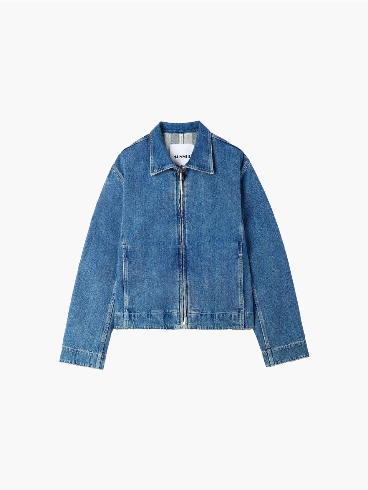 A light blue, organic bomber jacket made from raw denim, featuring a front zipper and long sleeves. The jacket includes a collar and two front pockets, exuding a casual, slightly faded look. A silicon Sunnei patch adds a unique touch, while the fabric tag inside the collar reads "Marni.