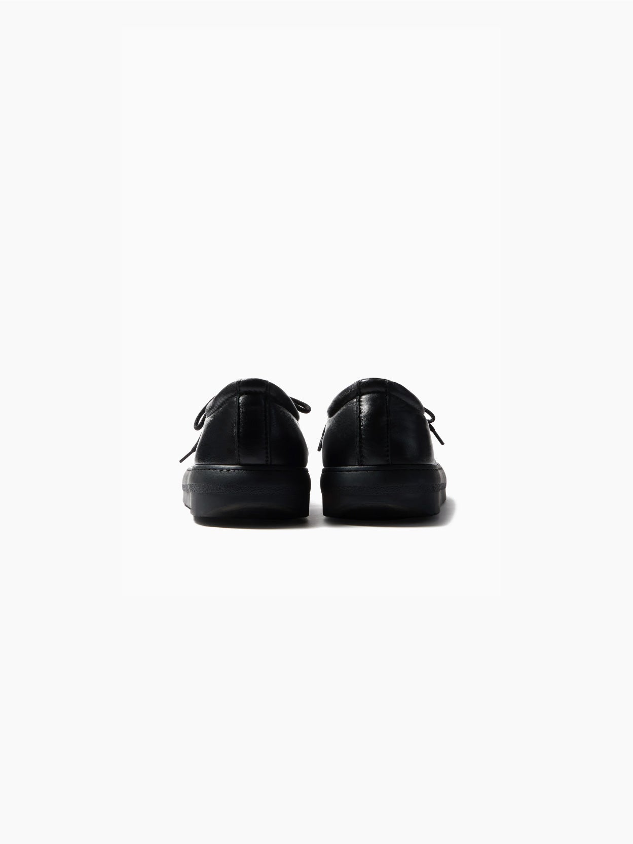 A side view of a single "Dreamy Bowling Black Shoe" by Sunnei on a white background. The sneaker features a low-top design with a smooth, minimalistic appearance, black laces, and a thick black sole. Made in Italy, the lace-up shoe appears to be made of a soft, suede-like material.
