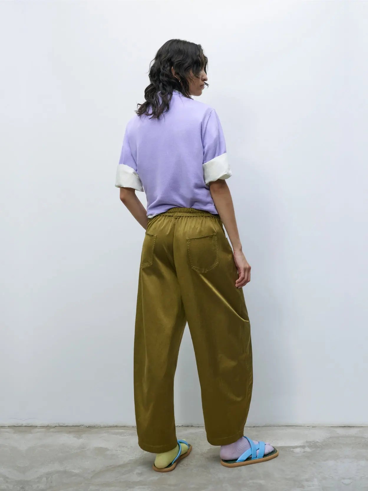 Satin Curved Pants Woodbine by Cordera with a relaxed fit and a slight taper at the cuffs. Featuring front pockets, a single-button closure, and a zipper fly. The fabric appears to be lightweight and slightly textured. Available exclusively at Bassalstore, your go-to shop in Barcelona for chic fashion finds.