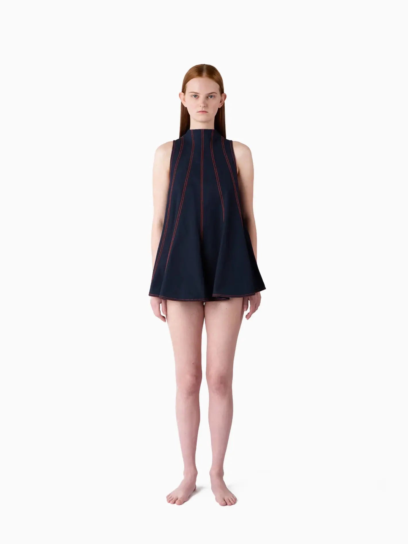 A sleeveless, navy blue Tulipano Top from Sunnei with red vertical stitching lines from the neckline to the hem. The top has a flared, A-line silhouette and is photographed against a plain white background. This stylish piece embodies the chic fashion of Barcelona.