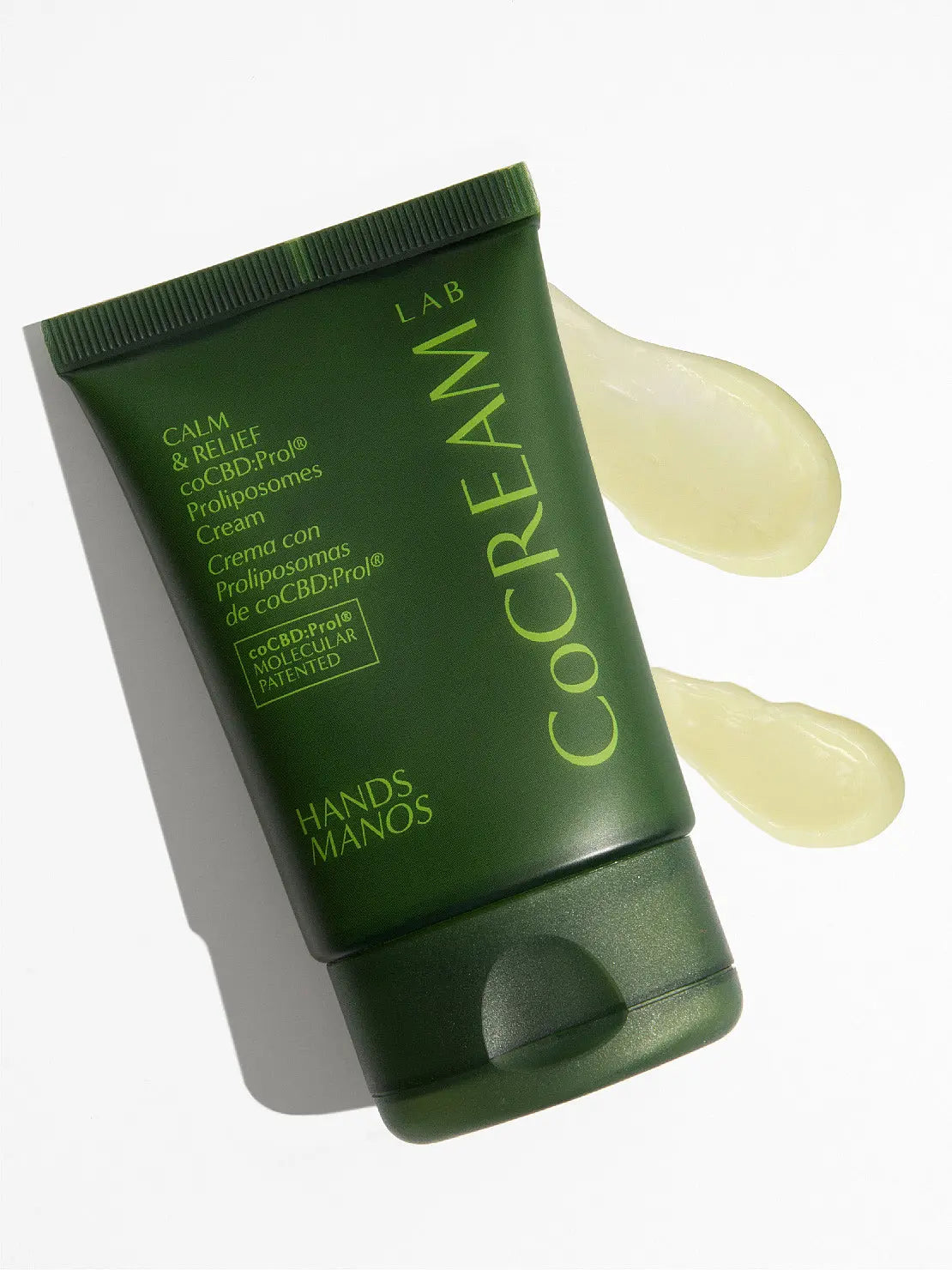 Green tube of Hands Cream 50ml by CoCream Lab, featuring a logo and text detailing it as a hand cream with "Calma & relief eccd-pro" Prolipsomes Cream formula. The tube, available at Bassalstore in Barcelona, has a flip-top cap and is standing upright against a plain background.