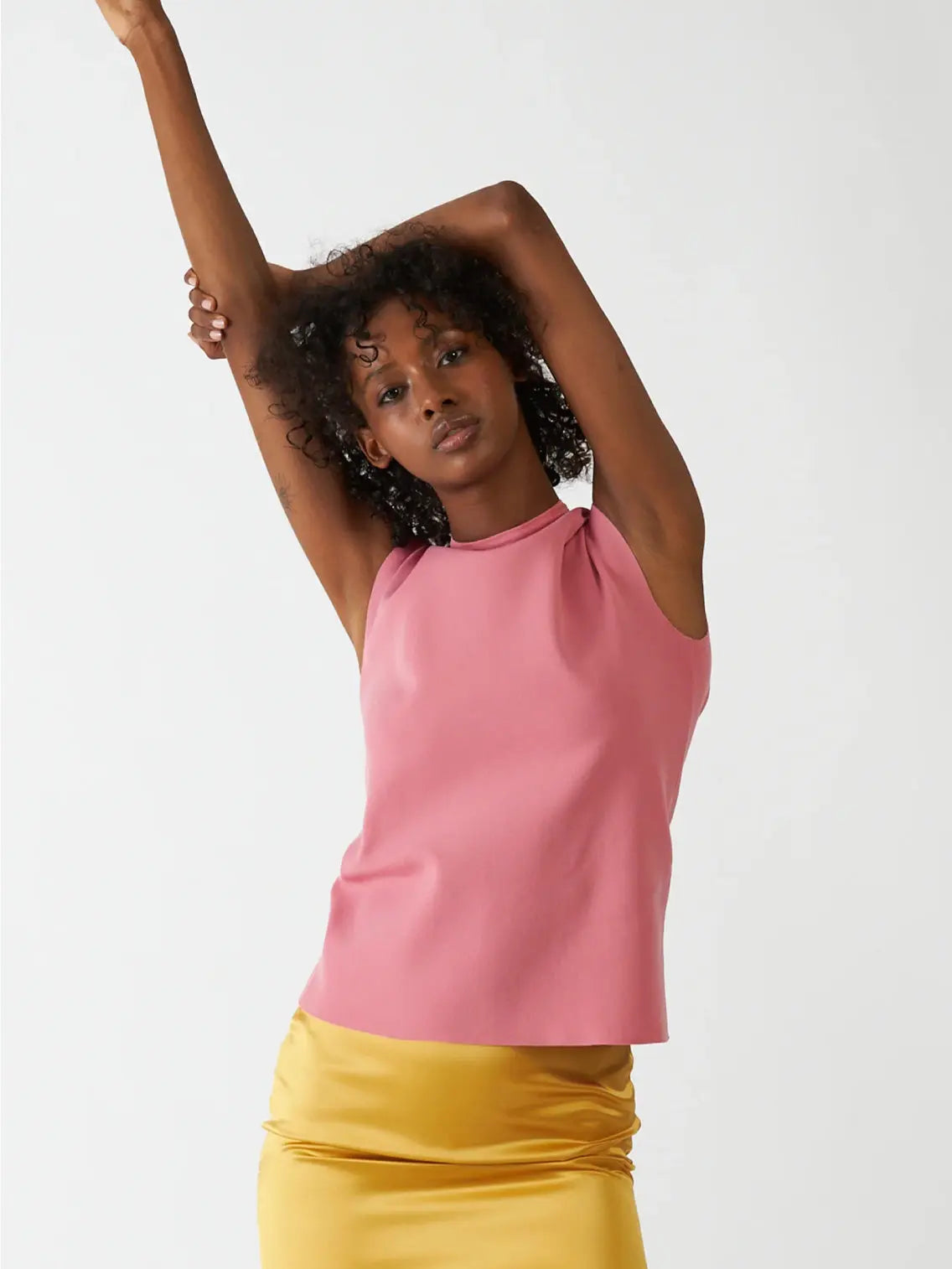 A Bielo Neru Top Pink with a high neckline and a back zipper closure. The lightweight, slightly textured fabric is perfect for warm days. Laid flat against a white background, this chic piece is available at BassalStore in Barcelona.