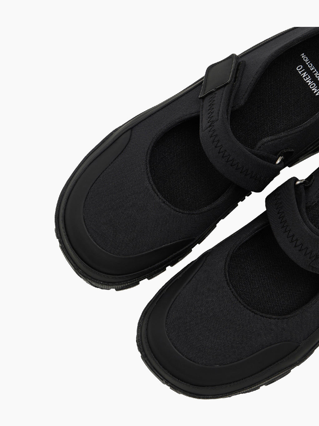 The Amomento Mary Jane Shoes Black feature a thick, rugged sole and a Velcro closing strap over the top. These shoes also include a pull-tab at the heel and have a logo on the side of the soft sole.