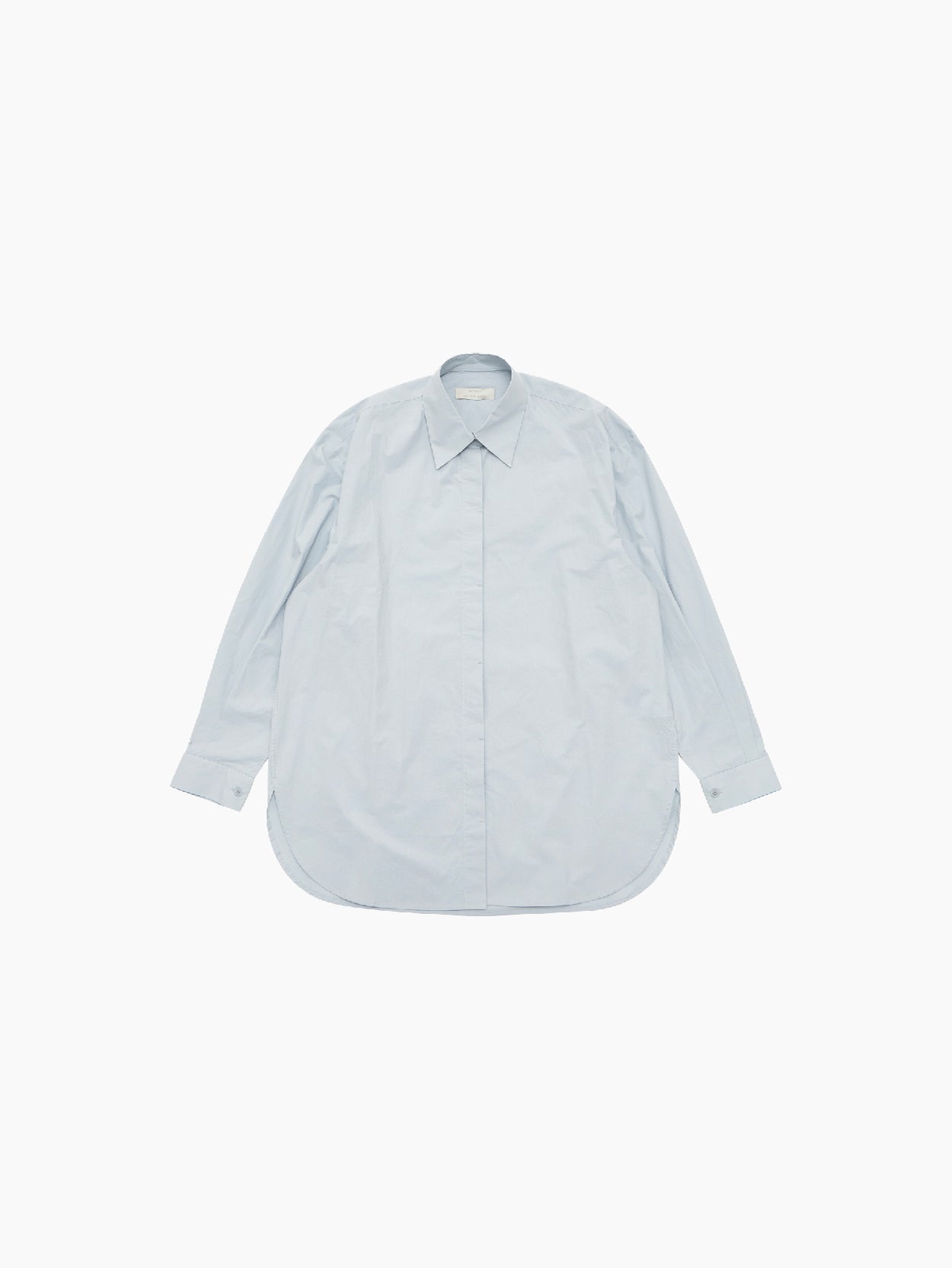 The "Oversized Shirt Light Blue" by Amomento is displayed flat on a white background. This light blue, long-sleeved button-up shirt features a classic collar and rounded hem. Crafted from high-density cotton, it boasts minimal design details for a clean and simple appearance.