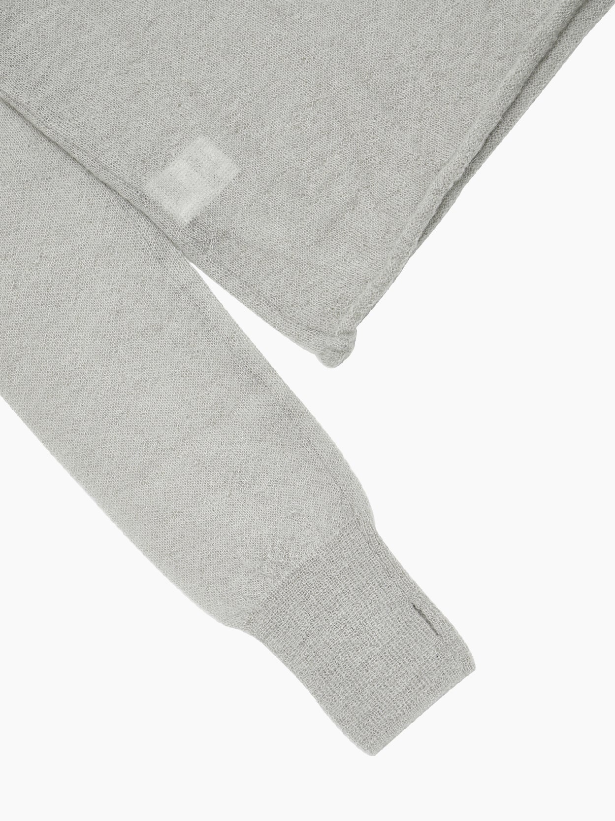 The Sheer Hooded Knit Light Grey by Amomento is a light grey, long-sleeved hooded sweatshirt featuring a wool-blended drawstring hood, ribbed waistband and cuffs, and a small white tag near the bottom hem on one side. The hoodie is laid flat against a plain white background.