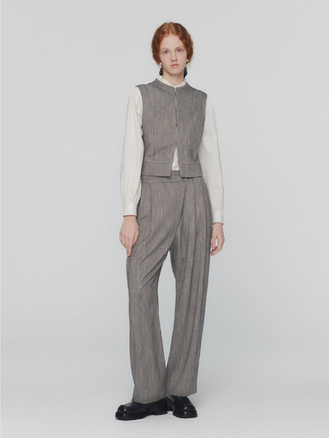 The Wool Tweed Motive Vest Grey by Amomento is a sleeveless, boxy, cropped vest made from a wool blend with a textured or woven appearance. It features subtle diamond-shaped stitch details and has a round neckline with no visible buttons or zippers on the front.