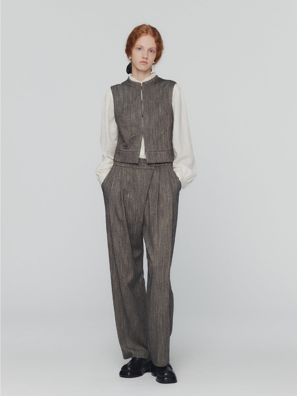 Amomento's Wool Tweed Wrap Pants in Charcoal feature a high-waisted wide-leg silhouette with a subtle herringbone pattern. These pants come with front pleats and practical pockets, crafted from wool-like fabric for a tailored and slightly textured appearance. With their simple, classic design, these pants offer a polished look.