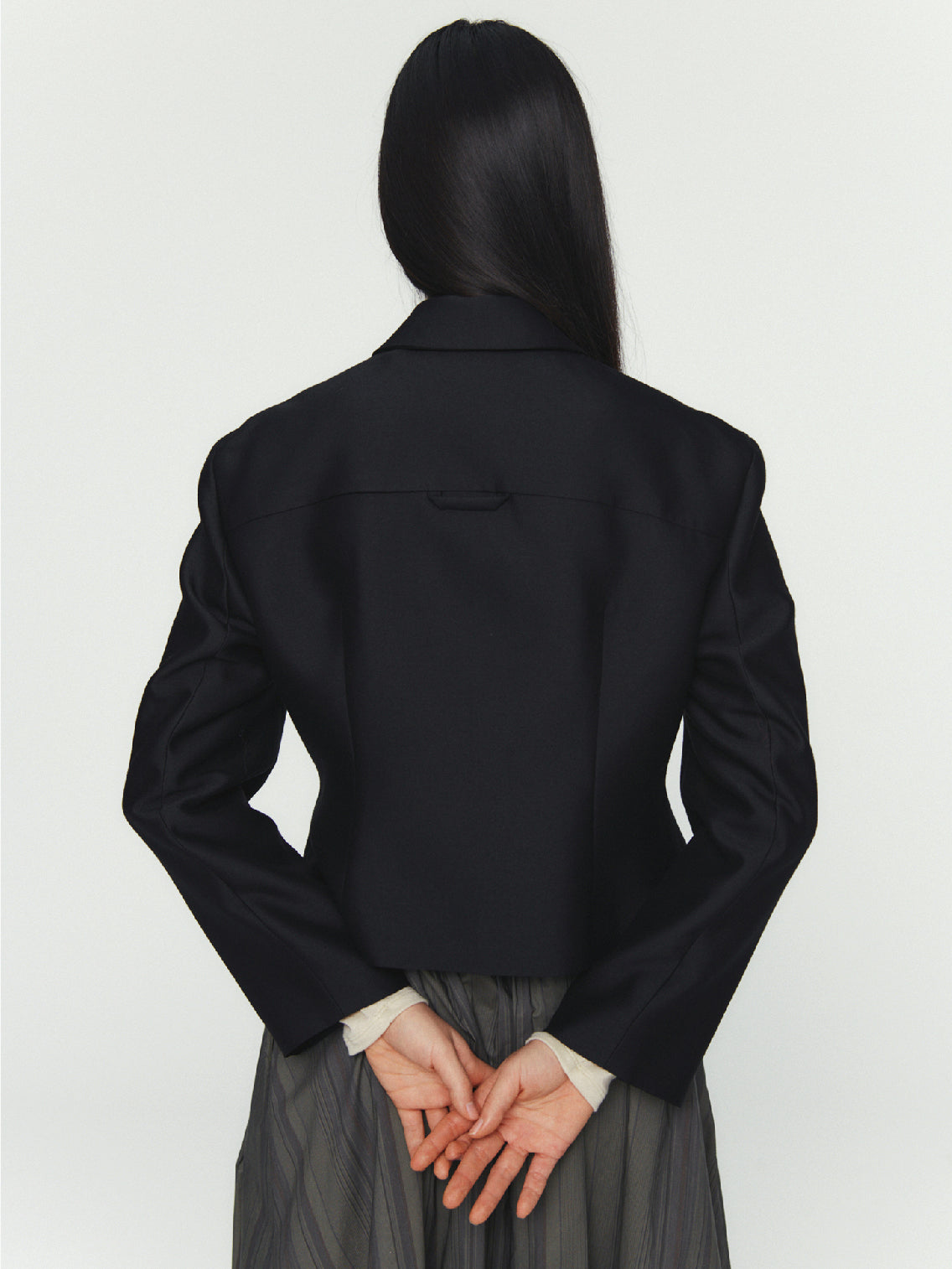 The Amomento Wool Silk Button Up Jacket Black is showcased against a white background. This black long-sleeve jacket features a classic collar and button-down front, crafted from soft wool silk. It boasts a fitted, tailored design that exudes sleek, minimalist style. The elegant silhouette epitomizes modern sophisticated fashion.