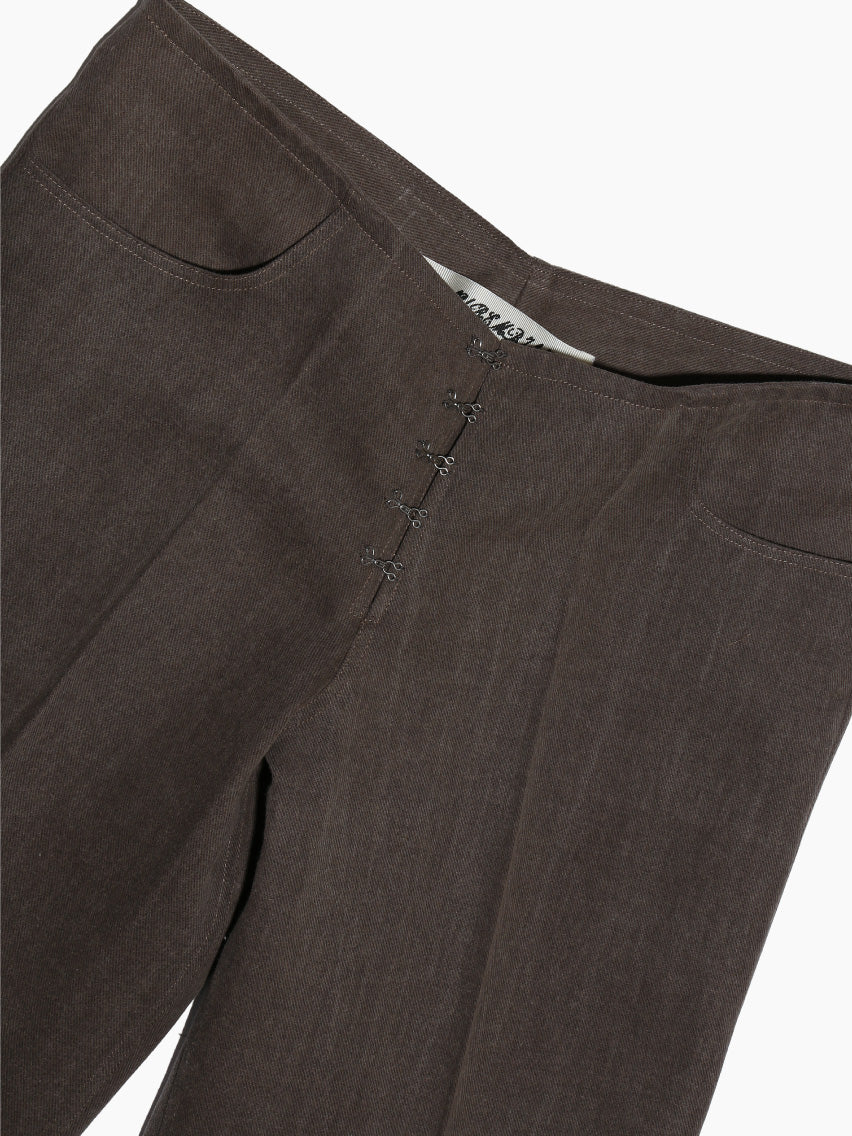 Aurembiaix's dark brown Denim Trousers feature a high waist and a subtle front zipper, offering a classic straight-leg silhouette with simple styling. Made of 100% cotton, these pants, shown laid flat against a white background, highlight their full length and timeless design accented by a hook and eye front fastening.