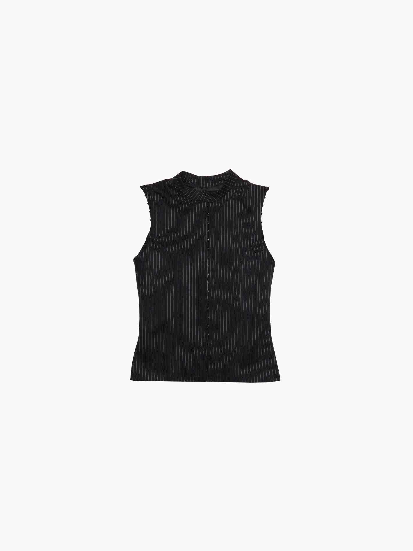 The "Pinstripe Doublet" by Aurembiaix is a long-sleeved, black button-up blouse featuring a subtle vertical pinstripe pattern. Made from 100% cotton, it boasts a small, rounded collar and offers a tailored fit with buttons running down the front.