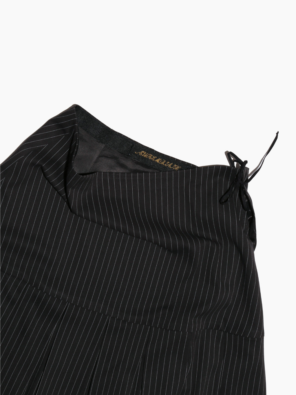 The Aurembiaix Pinstripe Pleated & Gathered Skirt is a black, pinstriped mini skirt with ruched sides and adjustable drawstrings for a side-gathered look. It features a slightly flared hem and is finished with a subtle hook-and-eye fastening for added detail against the white background.