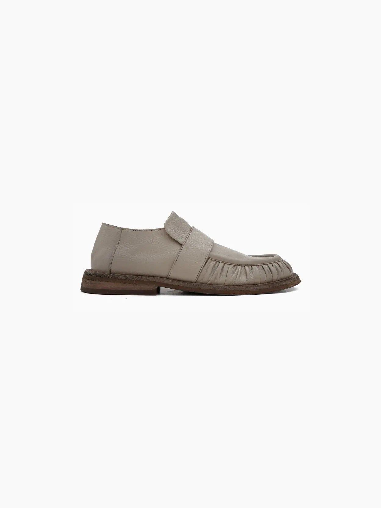A single Alluce Loafer Clay by Marsèll, viewed from the side, available at Bassalstore in Barcelona, features a wide strap across the upper and a gathered detail along the toe area. The shoe has a low, dark brown sole with a slightly worn appearance.