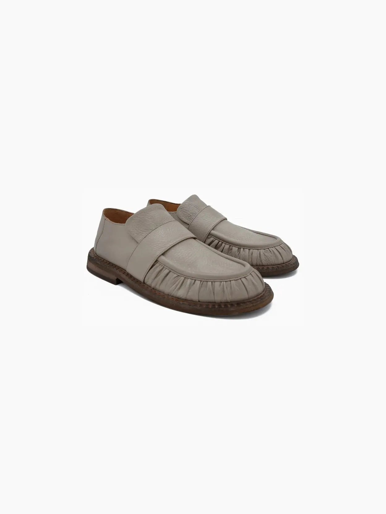 A single Alluce Loafer Clay by Marsèll, viewed from the side, available at Bassalstore in Barcelona, features a wide strap across the upper and a gathered detail along the toe area. The shoe has a low, dark brown sole with a slightly worn appearance.