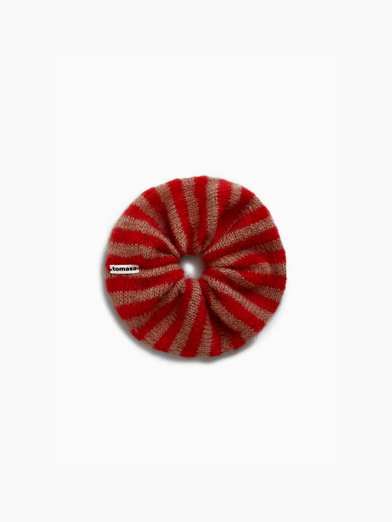 A round, knitted scrunchie with red and beige stripes is displayed against a plain white background. There is a small white tag with red and black writing attached to it. Shop the stylish Amapola Mohair Scrunchie by Tomasa at Bassalstore, your go-to store in Barcelona for unique finds.