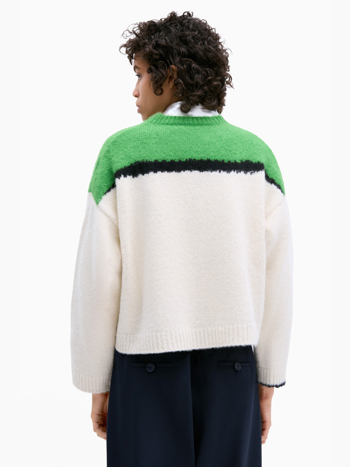 The Cordera Alpaca & Suri Sweater Bright Green is showcased against a plain backdrop, featuring a long-sleeve design with a loose, relaxed fit. The top portion of the sweater is bright green with a striking black stripe, while the remainder is cream-colored. It boasts a ribbed round neckline, cuffs, and hem. This beautiful piece is made in Spain.