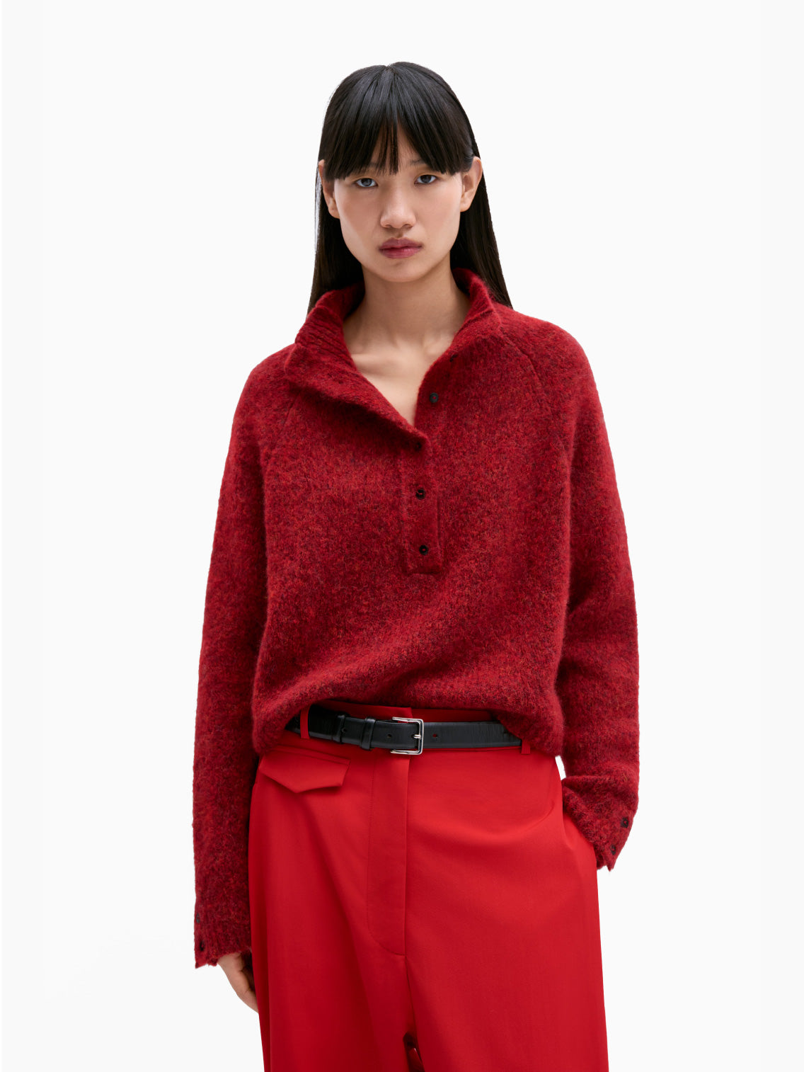 The Baby Alpaca Polo Sweater Dhalia by Cordera is a red, long-sleeve knit sweater with a round neck and a button-up front. This timeless piece features ribbed cuffs and hem, adding a cozy texture to the garment.