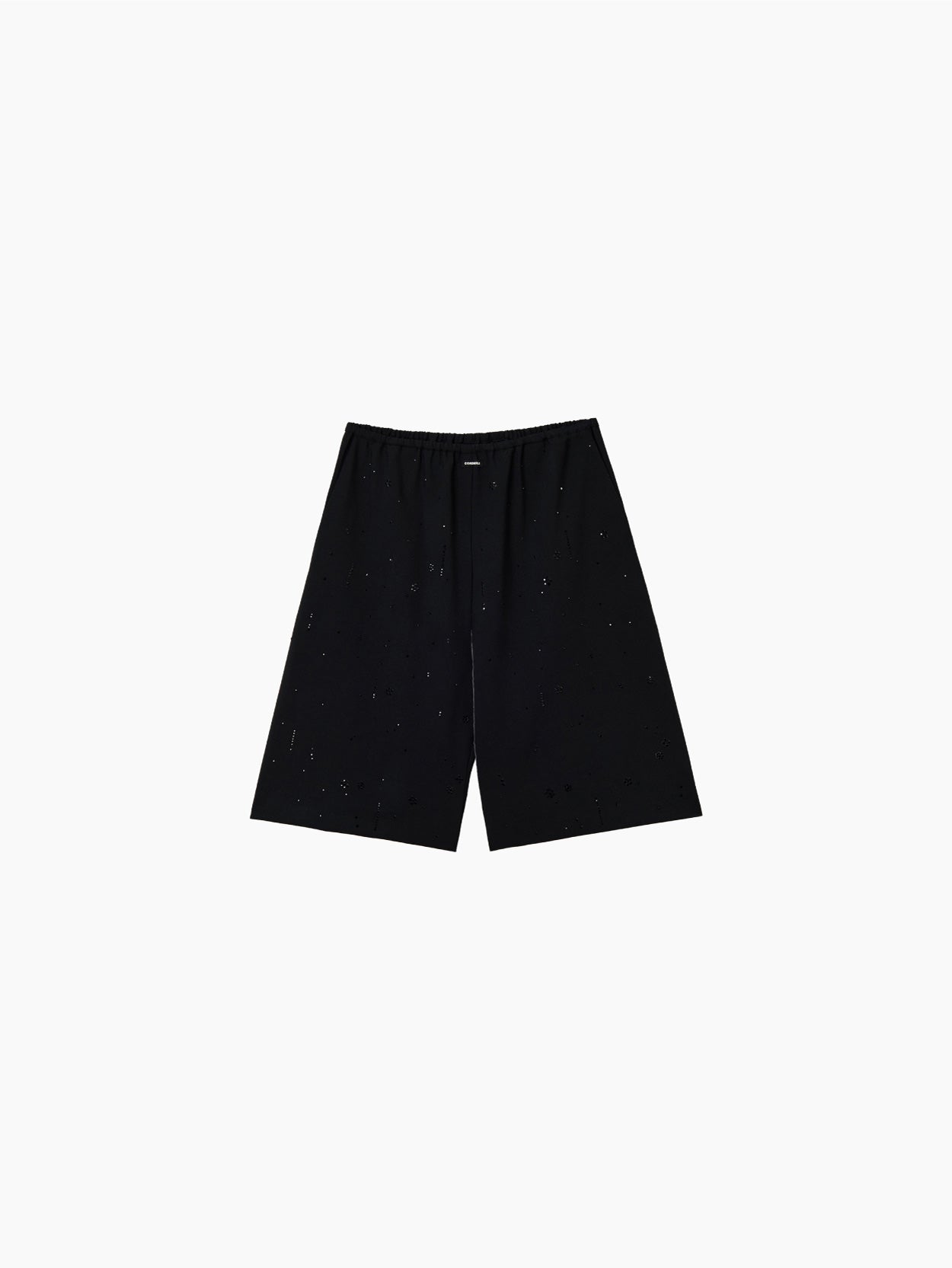 The Cordera Embellished Bermuda Black shorts are loose-fitting, knee-length black bermuda pants with an elasticated waistband. The fabric features a distressed, worn look adorned with scattered holes and frayed details. These shorts are showcased on a plain white background.