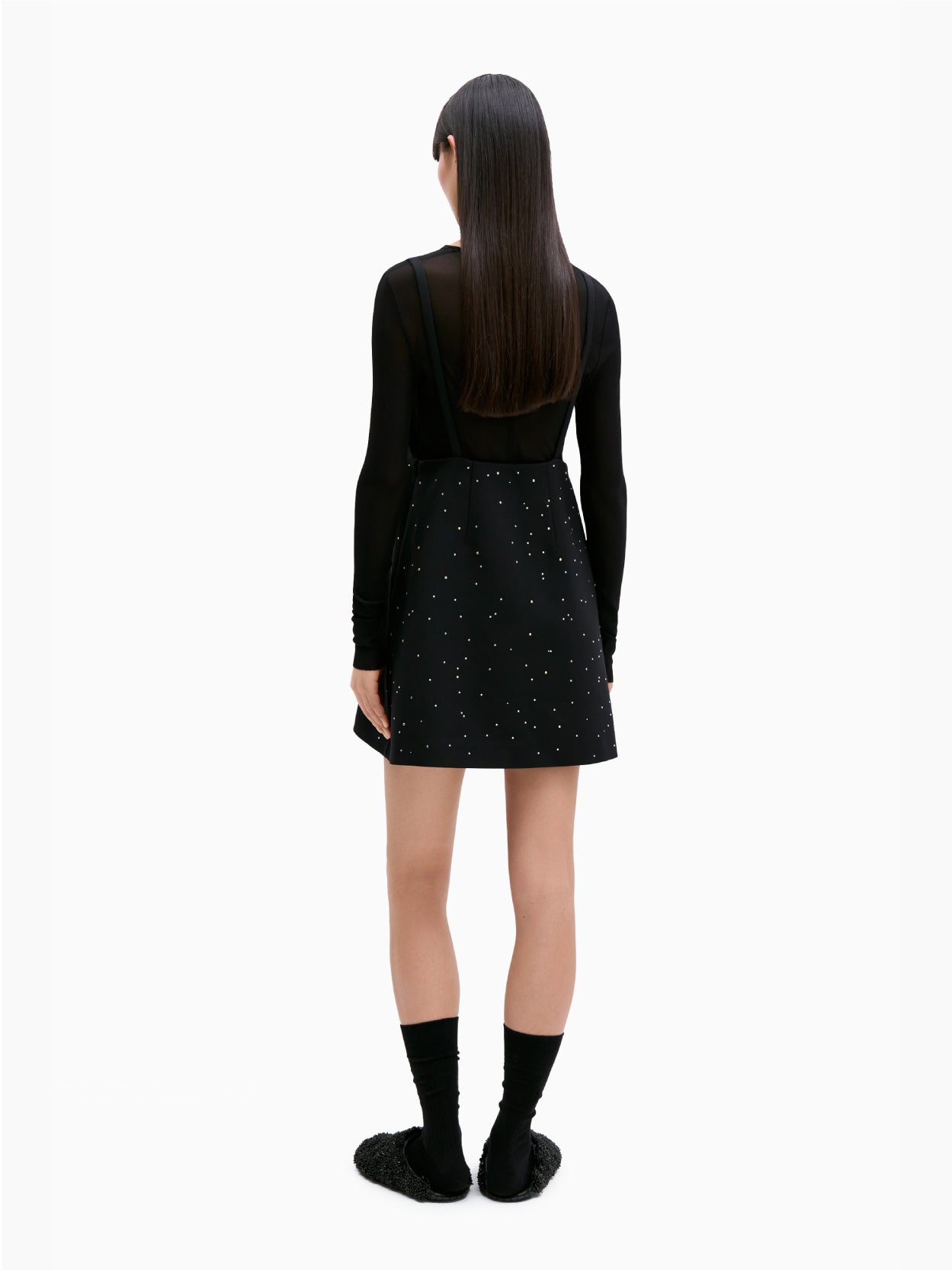 The Embellished Mini Dress Black by Cordera is a black sleeveless dress adorned with thin straps and small white star-like patterns scattered across the fabric. It features an open back, a square neckline, and an A-line silhouette.