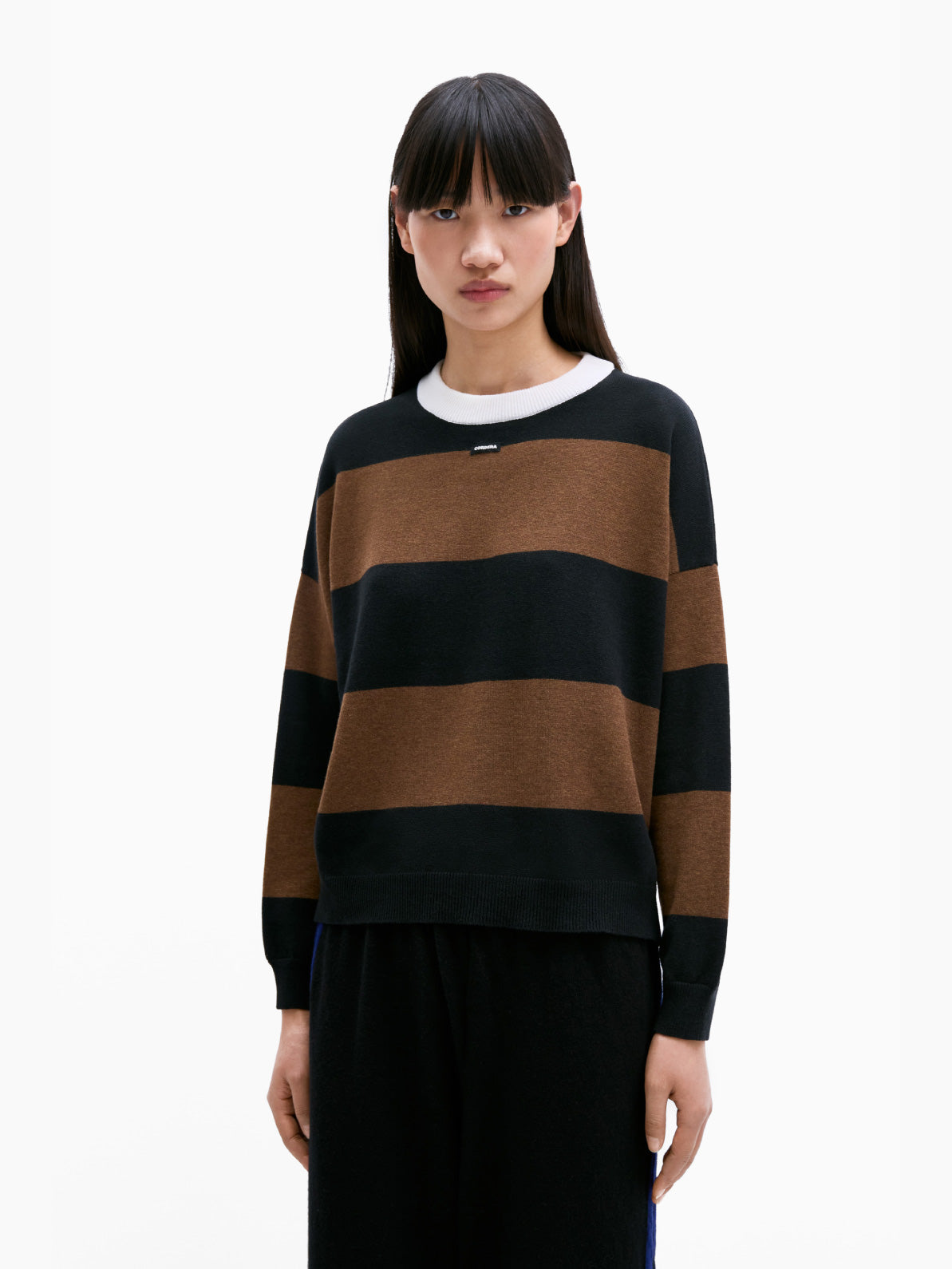 Introducing the Cordera Merino Wool Striped Sweater: a long-sleeve garment featuring broad, alternating black and brown horizontal stripes. Made from luxurious Merino wool, this sweater boasts a ribbed knit texture and a contrasting white crew neckline. Its simple and casual design makes it perfect for everyday wear.