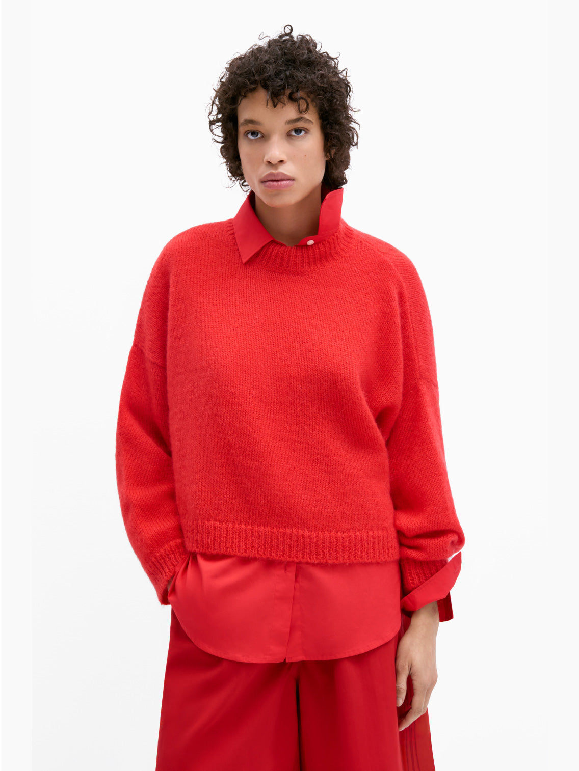 A vibrant red Mohair Sweater from Cordera, featuring long sleeves and a round neckline. This transitional knitwear showcases a ribbed collar, cuffs, and hem with a slightly loose and boxy fit. The fabric appears soft and cozy, crafted from mohair merino wool, making it perfect for cooler weather.