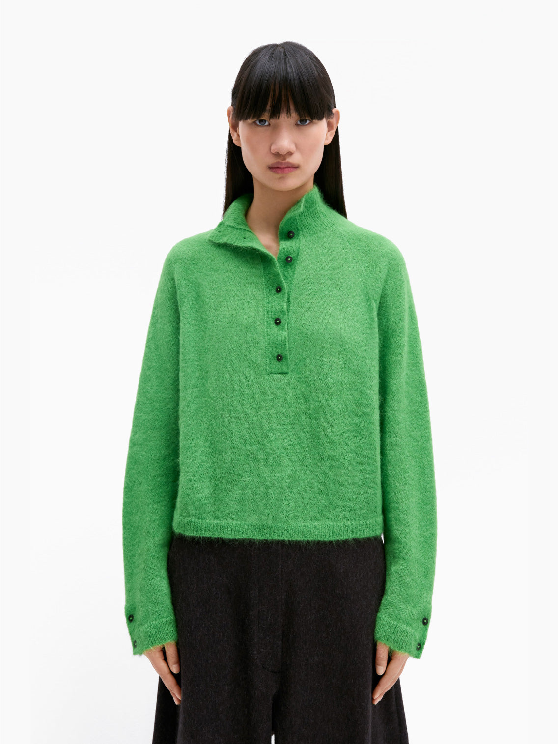 The Suri Polo Sweater by Cordera in bright green features long sleeves, a crew neck, and button detailing down the front and on the cuffs. This slightly cropped sweater has a soft, fluffy texture set against a plain white background.