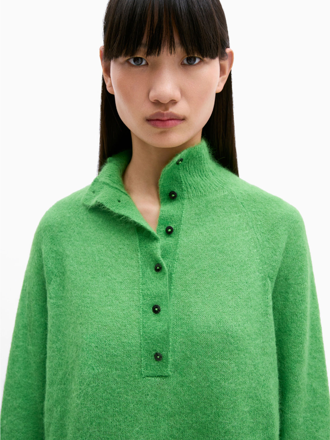 The Suri Polo Sweater by Cordera in bright green features long sleeves, a crew neck, and button detailing down the front and on the cuffs. This slightly cropped sweater has a soft, fluffy texture set against a plain white background.