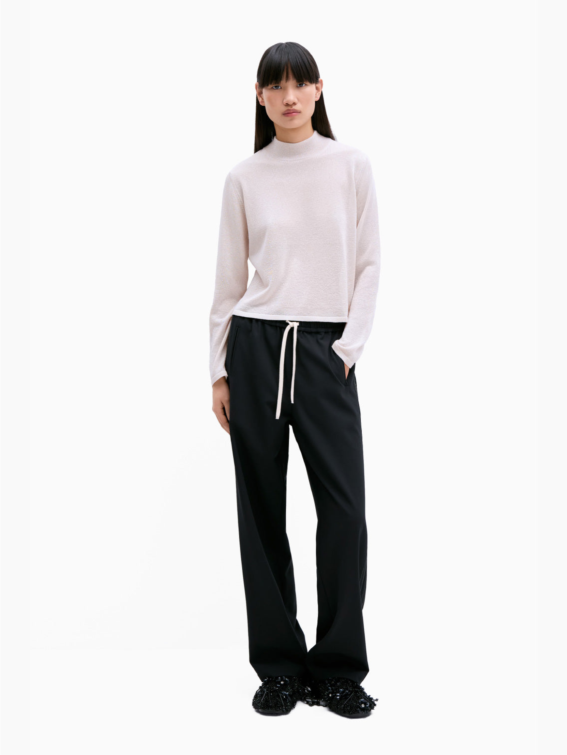 Cordera's Tailoring Drawstring Pants in Black feature an elasticated waistband with a white drawstring. These wide-leg pants have subtle white stitching along the sides and provide a relaxed fit. Their contemporary design is highlighted as they are laid flat against a white background.