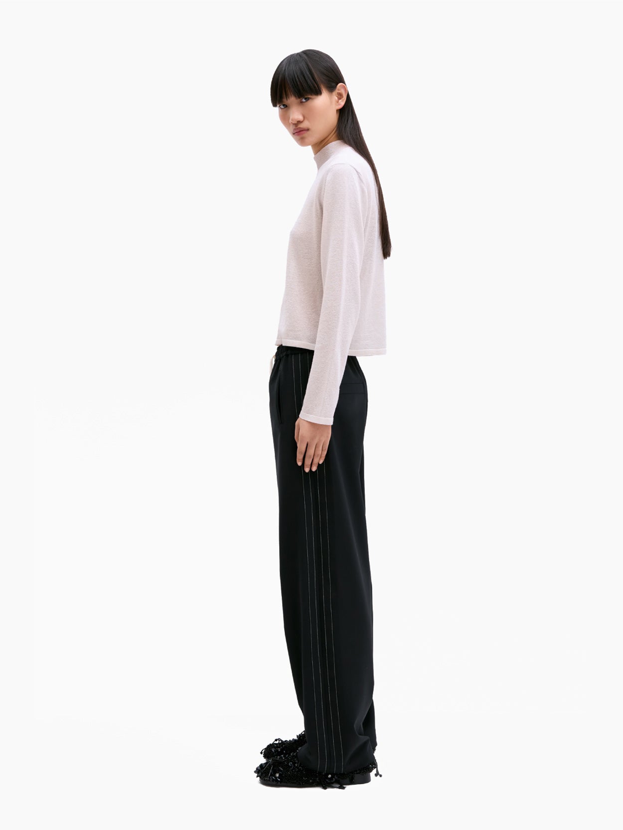 Cordera's Tailoring Drawstring Pants in Black feature an elasticated waistband with a white drawstring. These wide-leg pants have subtle white stitching along the sides and provide a relaxed fit. Their contemporary design is highlighted as they are laid flat against a white background.