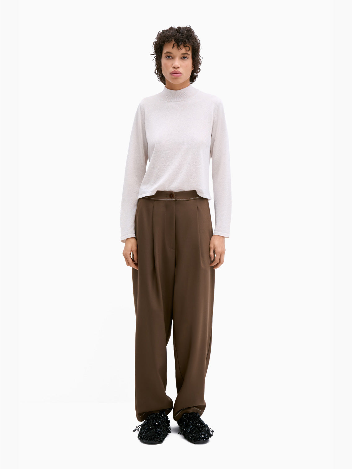 The Tailoring Stitch Pants Otter by Cordera are a pair of dark brown wide-leg pants featuring pleats at the waistband and a button-zipper closure. Crafted from tailored fabric, these cropped ankle pants are wardrobe staples with their smooth texture and contemporary design.