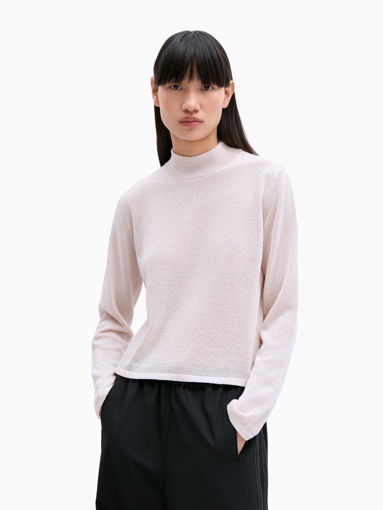 The Cordera Viscose Shimmery Turtleneck Sweater, featuring a beige hue and long sleeves, is showcased against a plain white background. This sweater boasts a simple, minimalist design with a slightly cropped length and no visible patterns or embellishments.