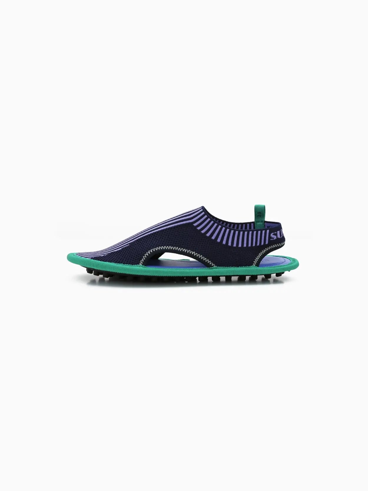 A single blue and green slip-on athletic shoe with a sock-like upper design and a flexible sole featuring prominent tread. The shoe displays cut-out details on the sides and a small loop at the heel for easy wearing, available exclusively at bassalstore in Barcelona. This is the Chiodi Knit Flat by Sunnei.