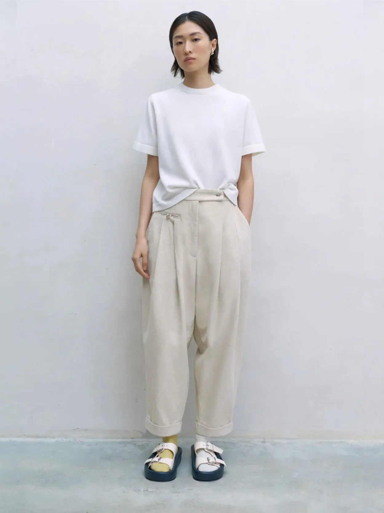 A pair of beige, high-waisted Corduroy Carrot Pants by Cordera with a pleated front and a relaxed, tapered fit. The pants feature a waistband with belt loops and a double-button closure. The legs end in simple cuffs, giving them a polished yet comfortable look, available now at Bassal Store in Barcelona.