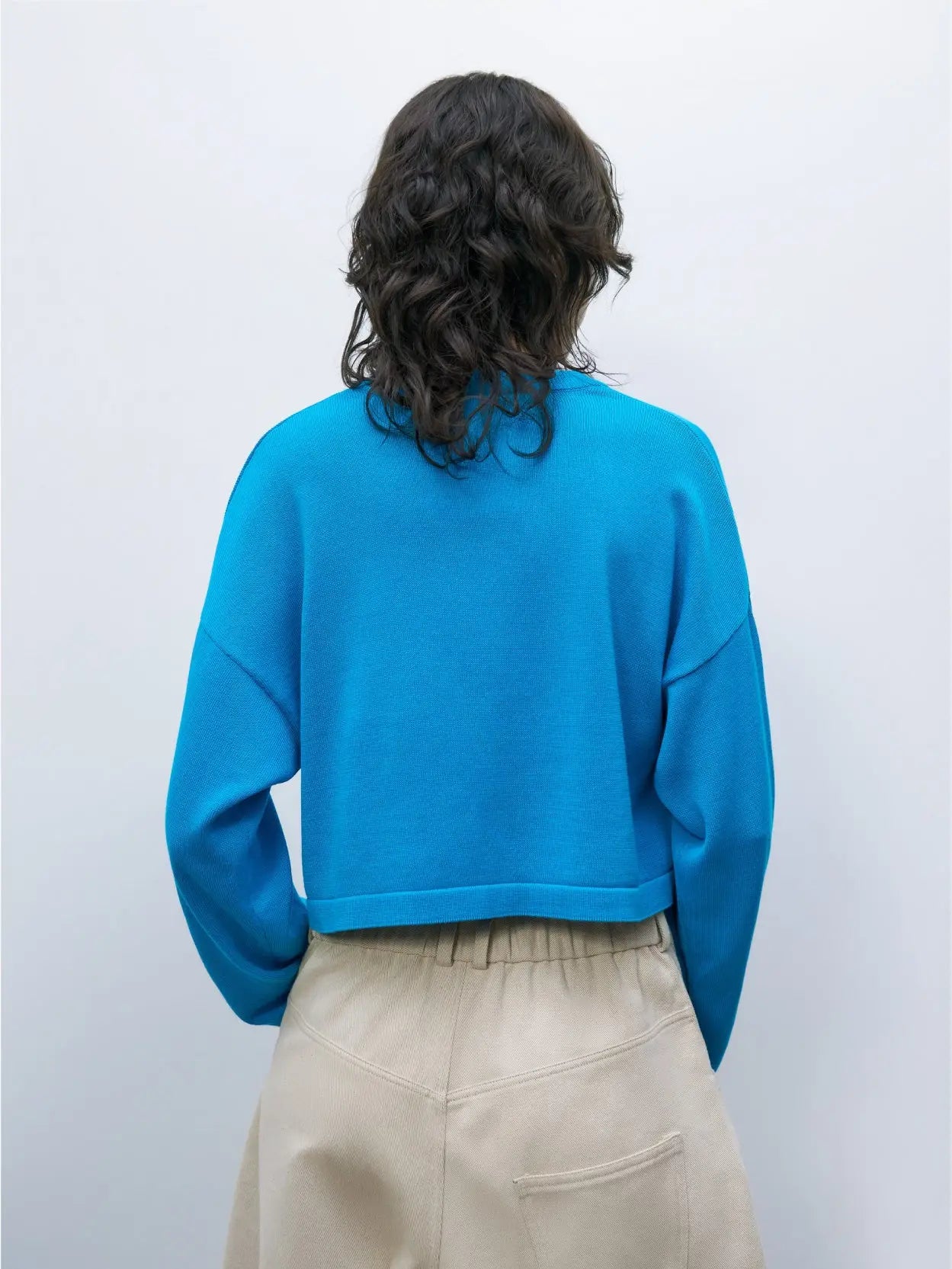A bright blue, long-sleeve Cotton Cropped Cardigan Ceruleo with a round neckline and black buttons down the front, available exclusively at Bassalstore in Barcelona. The cardigan is displayed against a white background.