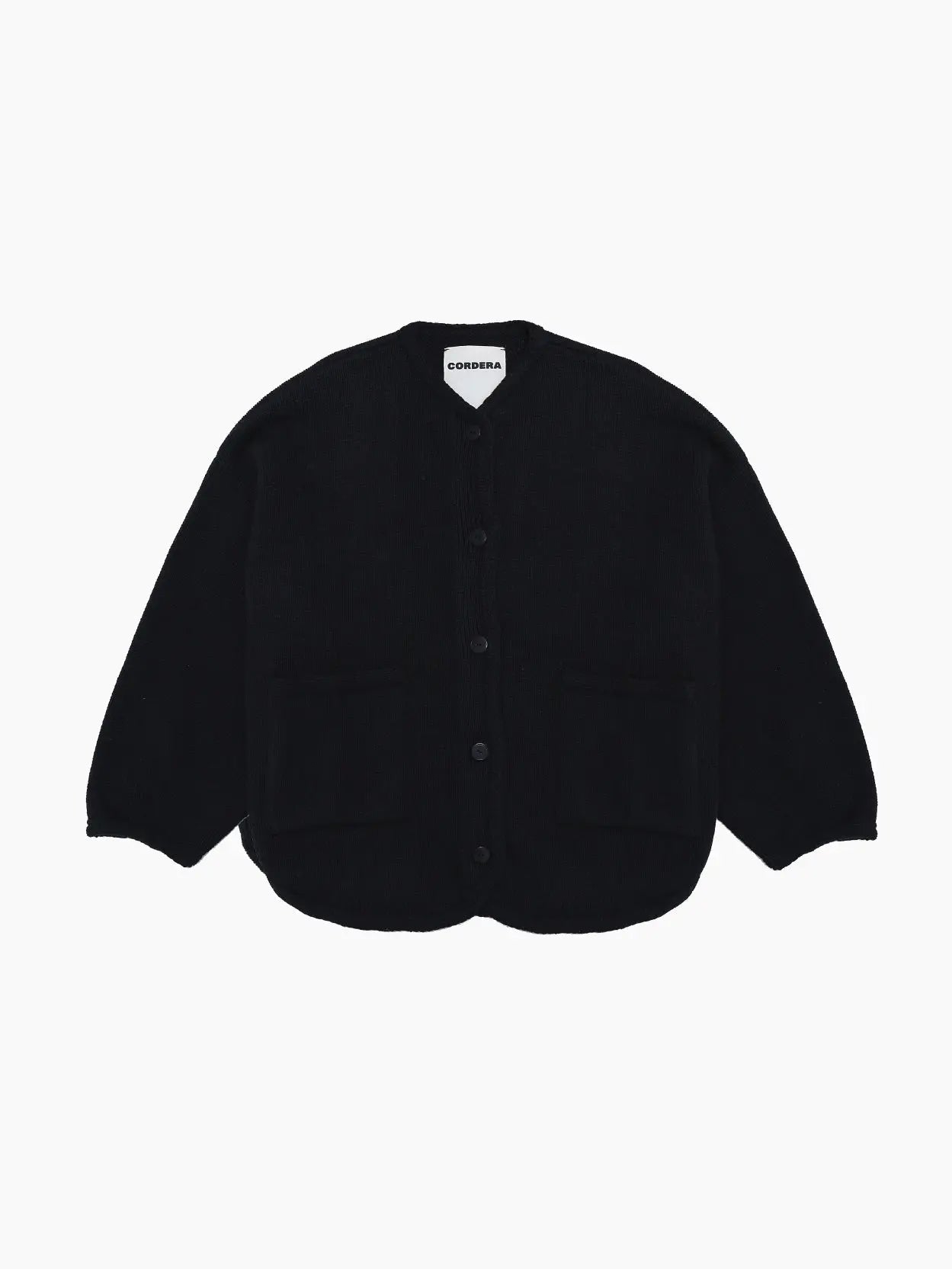 A black, long-sleeved Cotton Jacket Black with a round neckline, button-down front, and two front pockets. The jacket appears to be made of thick, cozy fabric, ideal for cooler weather. The label inside the collar reads "Cordera," available at Bassal Store in Barcelona.