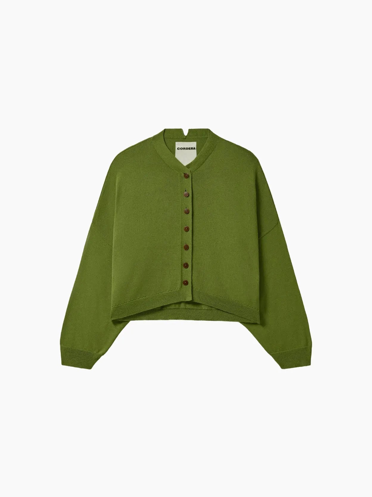 A green cropped cardigan with a V-neckline and brown buttons down the front is featured. The sleeves are long, and the fabric appears to be knit. The Cotton & Cashmere Cardigan Woodbine by cordera, available at Bassalstore Barcelona, has a label at the inner neckline. The background is white.