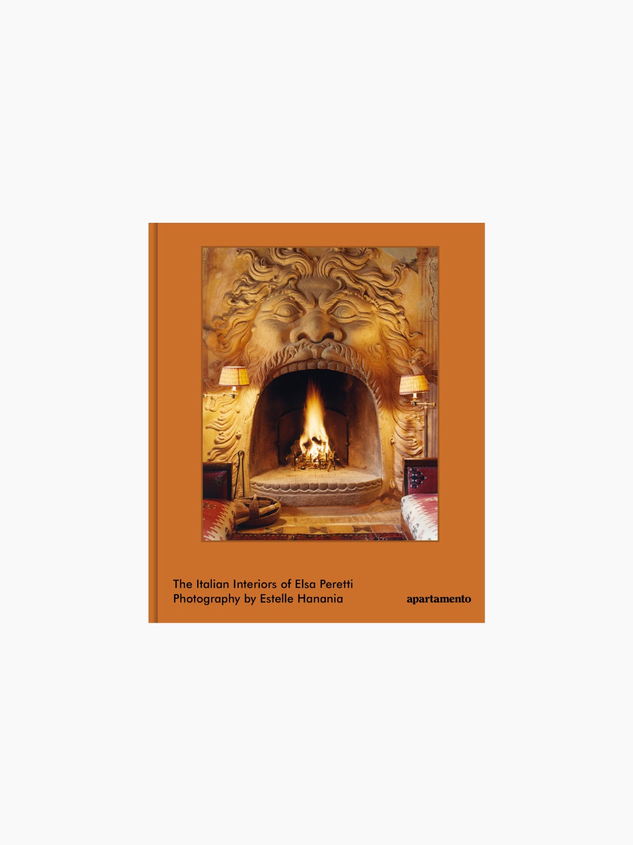 Apartamento's book cover titled "The Italian Interiors of Elsa Peretti" features photography by Estelle Hanania. The cover showcases a lavish fireplace designed to resemble a roaring lion's head with flames inside, flanked by lamps and a cozy seating area.