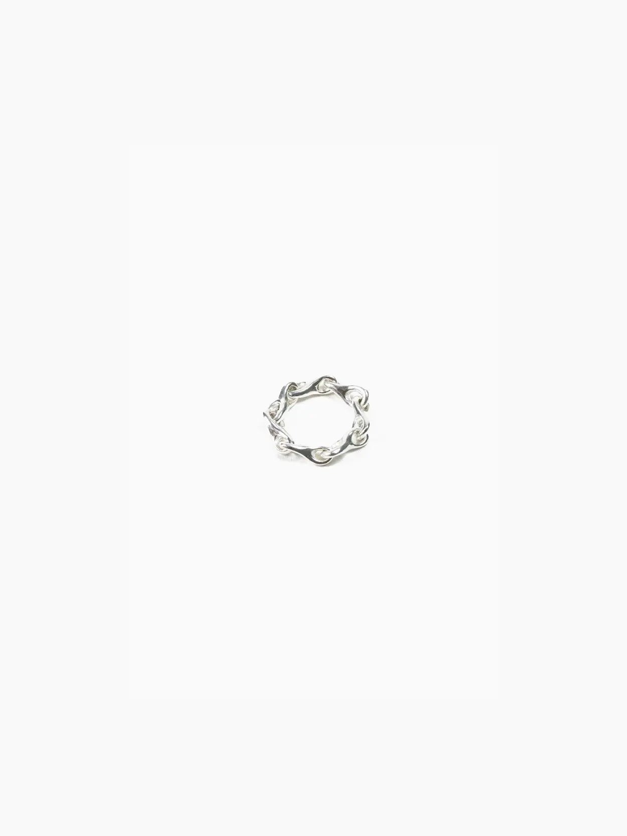 A silver Elo Chain Ring with an intricate, wavy design sits against a plain white background. Available at Bassalstore in Barcelona, the ring's band features interconnected loops and curves, giving it an elegant and unique appearance. Created by Nathalie Schreckenberg.