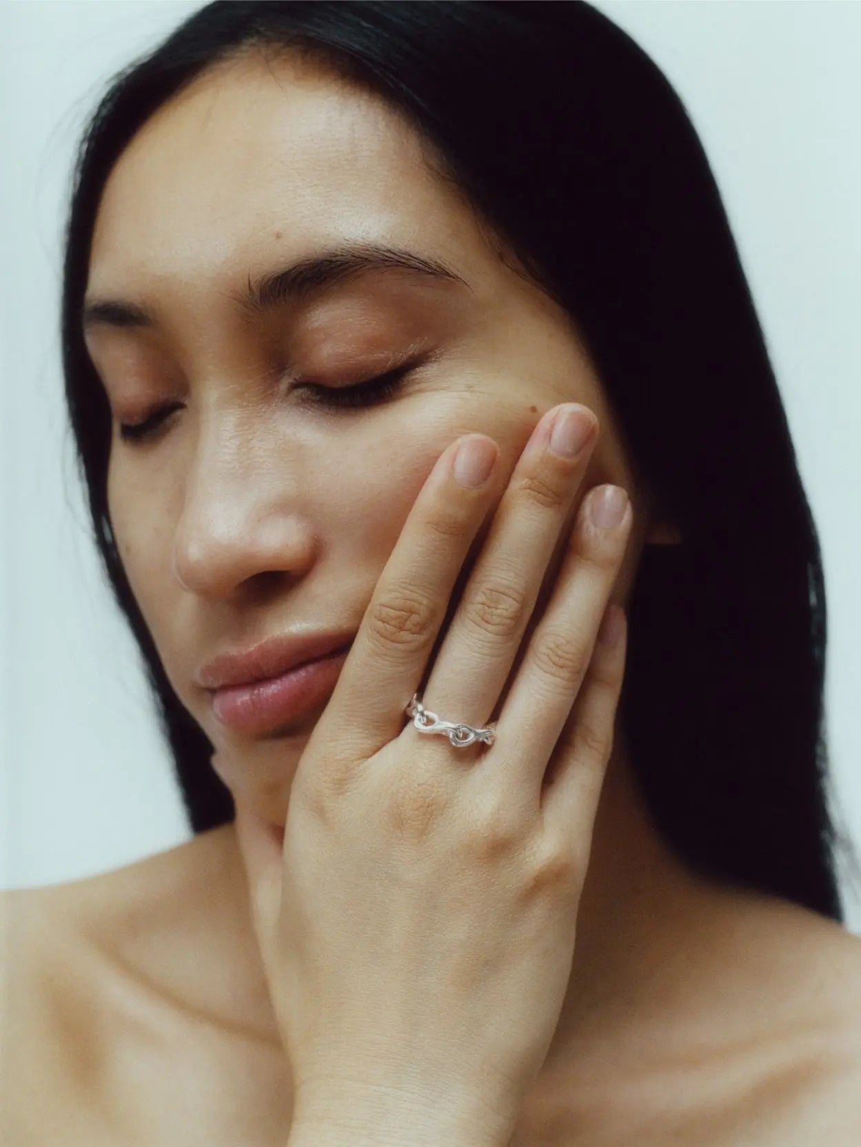 A silver Elo Chain Ring with an intricate, wavy design sits against a plain white background. Available at Bassalstore in Barcelona, the ring's band features interconnected loops and curves, giving it an elegant and unique appearance. Created by Nathalie Schreckenberg.