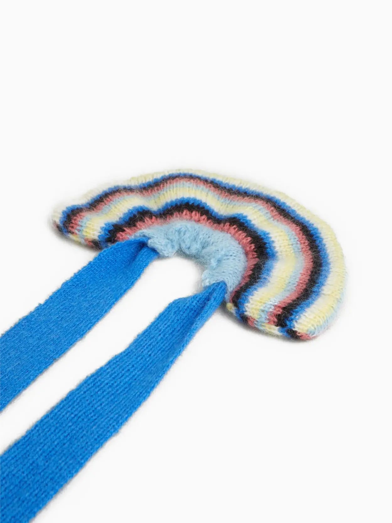 An Elvira Bow Scrunchie by Tomasa resembling a rainbow with pastel colors, transitioning from light to dark hues. It has a light blue center and a bright blue tied end, with a small white label. The background is plain white, perfect for showcasing this charming accessory available at Bassalstore in Barcelona.