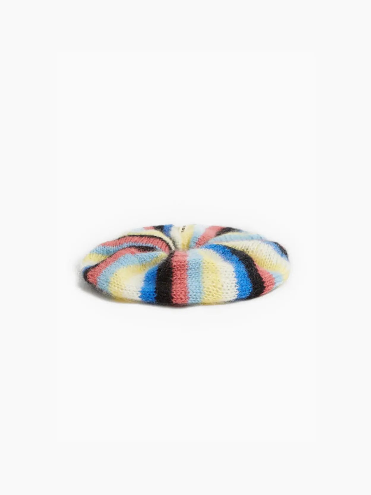 A colorful scrunchie with alternating stripes of blue, yellow, pink, black, and white, knitted from soft, fuzzy material, is displayed against a white background. The Elvira Mohair Scrunchie by Tomasa is available exclusively at Bassalstore.