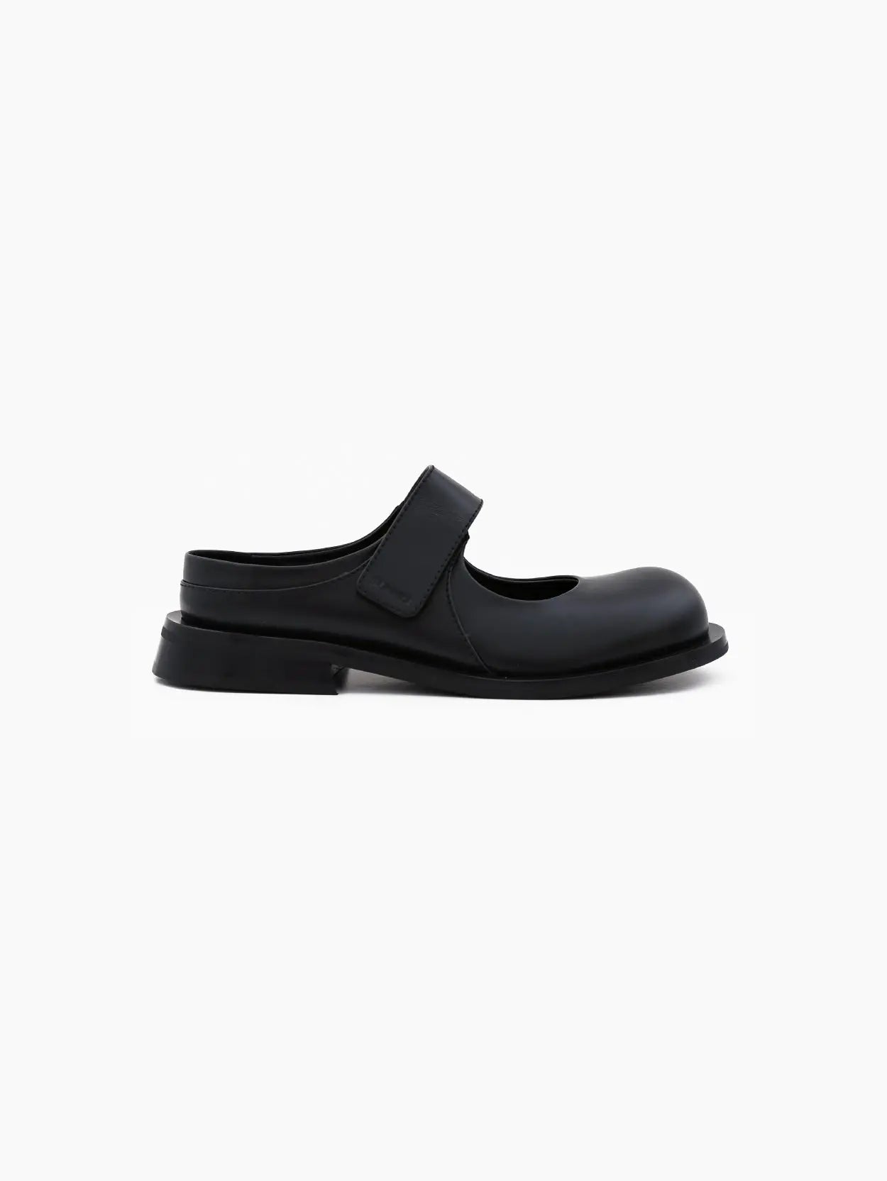 Image of a single black Sunnei Form Marg Black shoe viewed from the side, available at Bassalstore in Barcelona. The shoe features a rounded toe, a thick strap across the top with a velcro closure, and a chunky sole. The background is plain white.