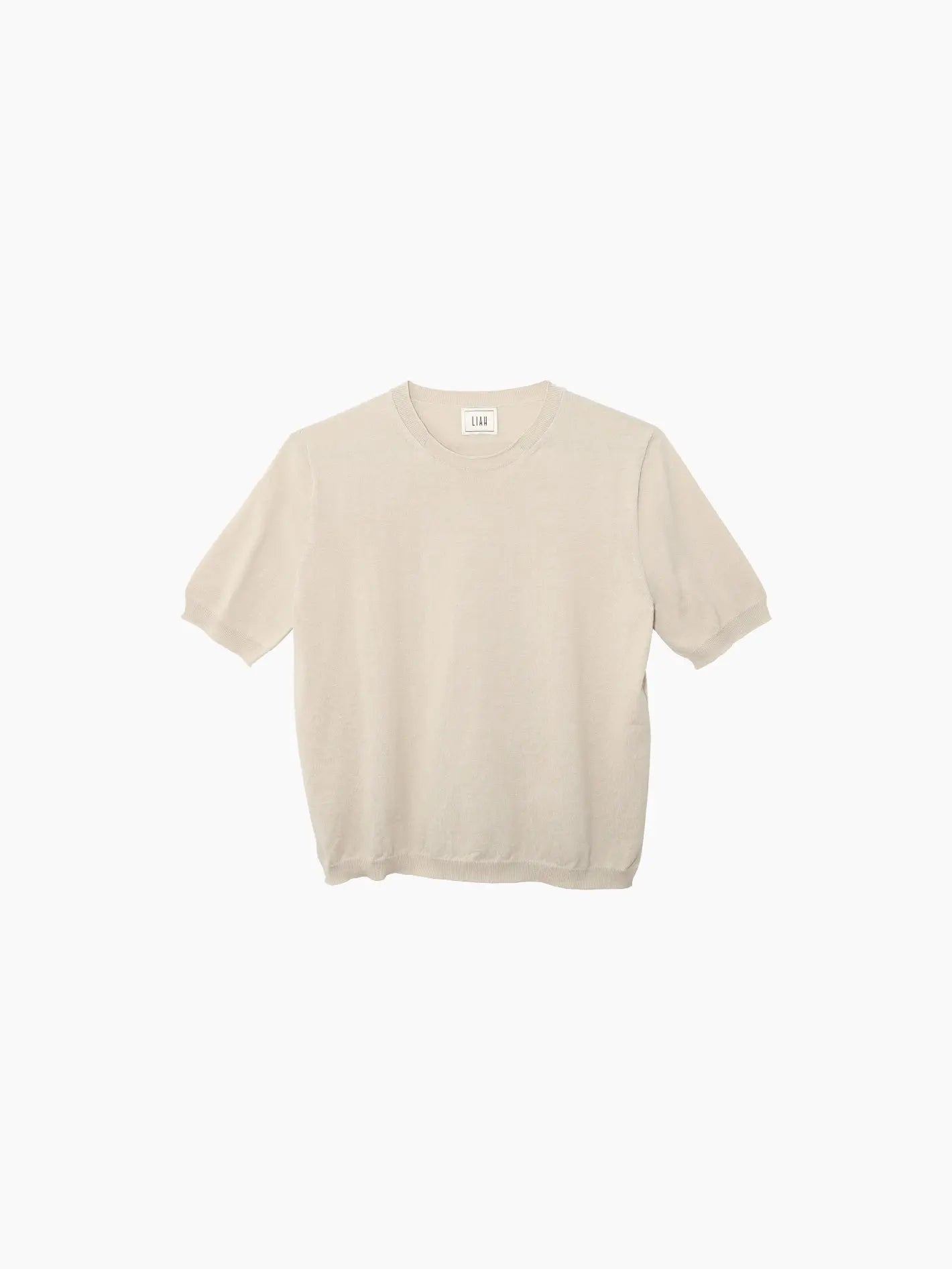 A beige short-sleeve sweater made from a soft, lightweight material. It has a simple, minimalist design with a round neckline and a loose fit, displayed against a plain white background. The Gia T-Shirt Tea by Liah is available exclusively at Bassalstore in Barcelona.