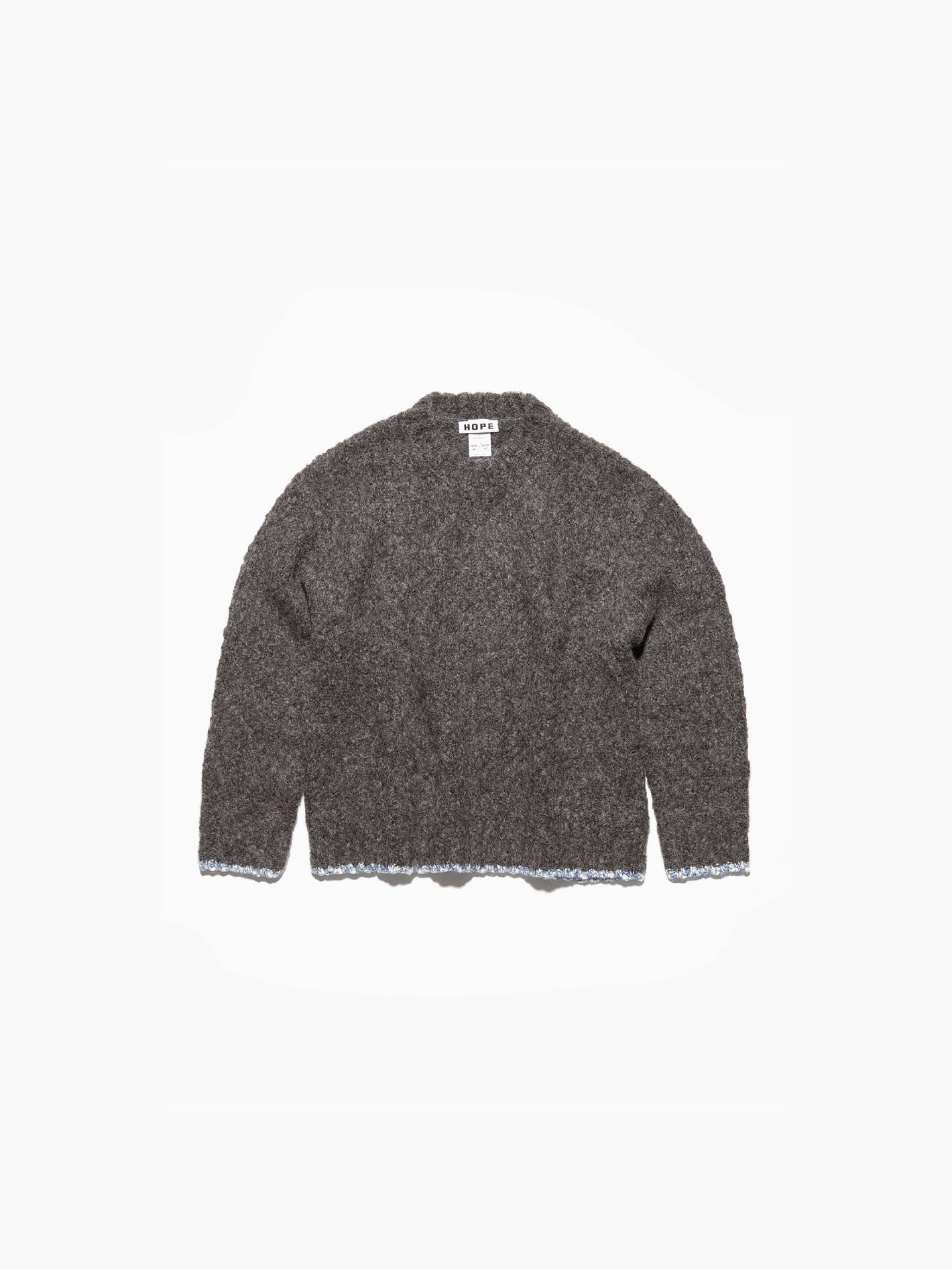 The Hope Box Sweater Grey, made from luxurious alpaca yarn, showcases a charcoal gray hue with subtle blue edging at the hem and cuffs. This knitted crewneck features a ribbed texture and classic design, laid flat against a white background.