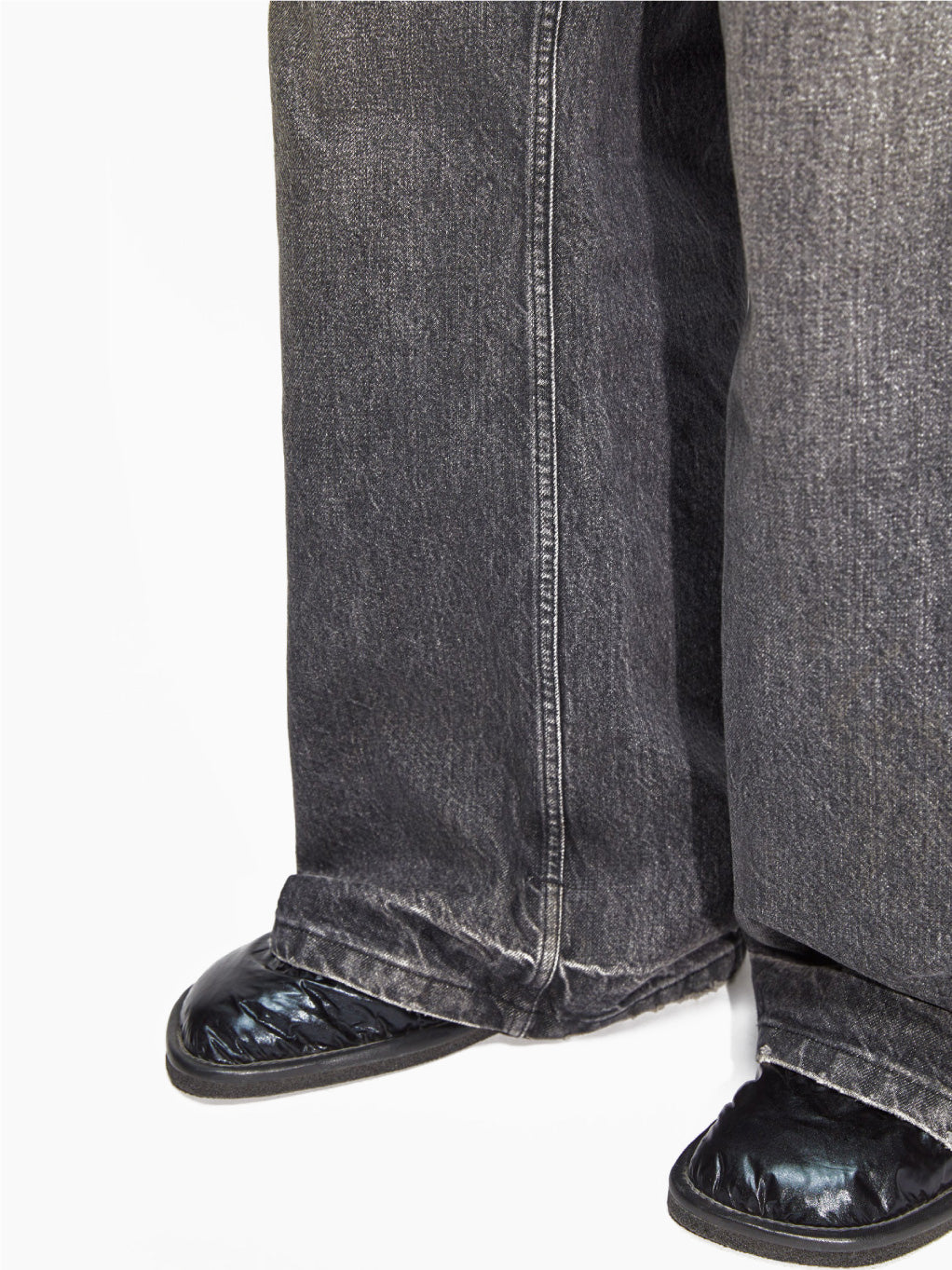 A person wearing Hope's Skid Jeans Heavy Black Vintage, which are loose-fitting and high-waisted with a slightly frayed hem. They are also sporting black shoes, while their upper body and head remain out of the frame against a plain white background.