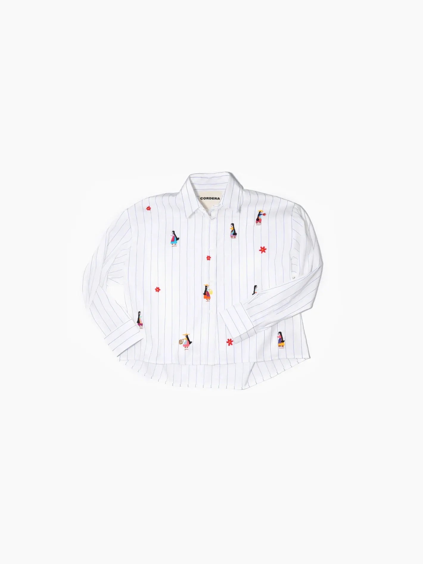 A Cordera Hand-Embroidered Shirt, available at bassalstore, is laid flat against a plain white background. It is a white long-sleeved button-up shirt with thin vertical stripes and various multicolored embroidered figures and red stars scattered across the fabric.