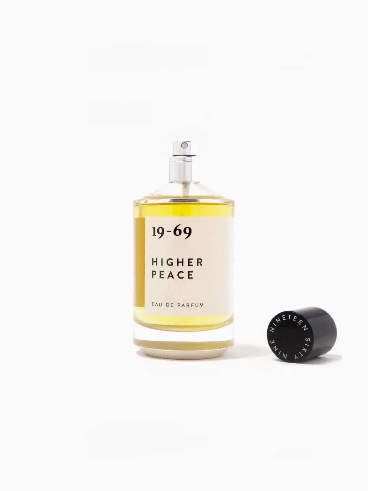 A bottle of perfume with a yellow liquid inside. The label reads "Higher Peace 100ml." The bottle, available at Bassalstore in Barcelona, features a black cap and minimalist design against a plain white background.