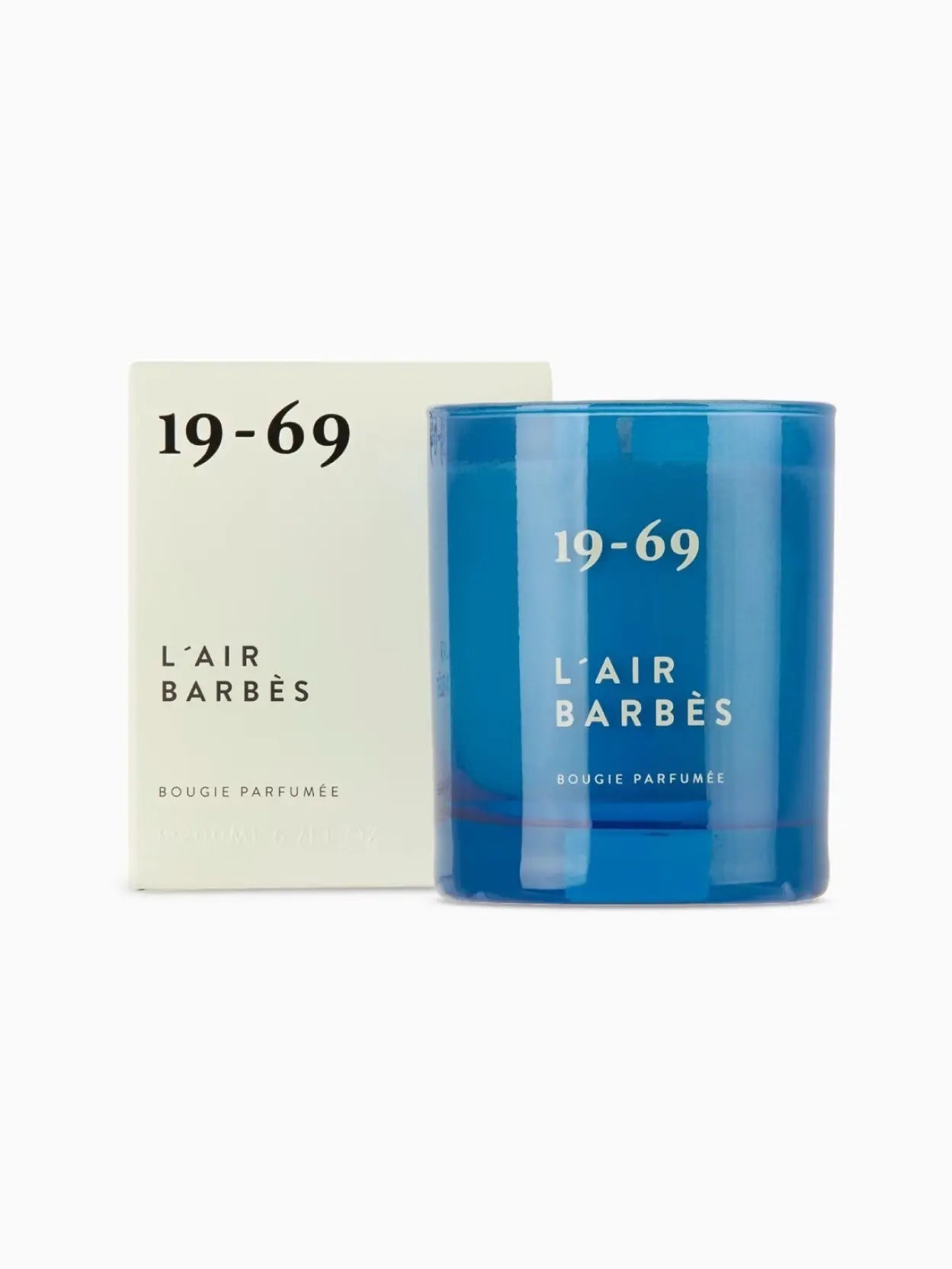 A blue candle with the label "19-69 L'Air Barbès Candle 200ml" printed in white. The candle, available at Bassalstore in Barcelona, is housed in a transparent blue glass container and sits against a plain white background.
